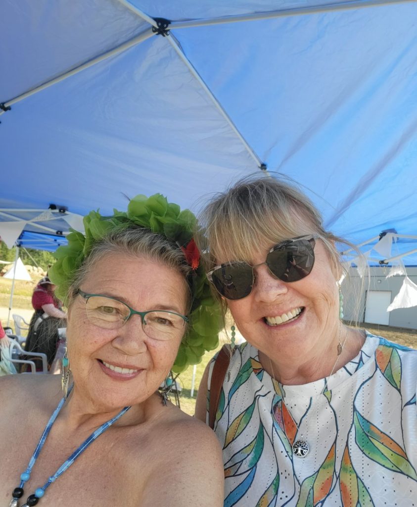 The artists Kathy and Melinda are smiling into the camera with their heads together.